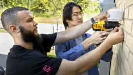 Doctoral candidate Alfredo Rodriguez, foreground, and Qingxuan Sun, a visiting Ph.D., install an Internet of Things-based outdoor air quality monitor in summer 2019.